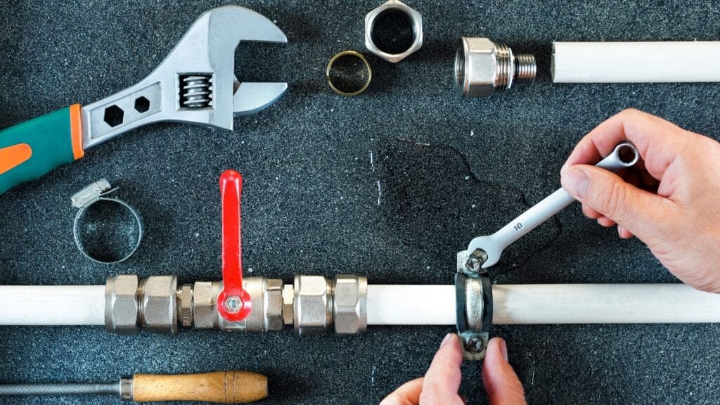 Plumber repairing a pipe valve with an adjustable wrench in Warminster