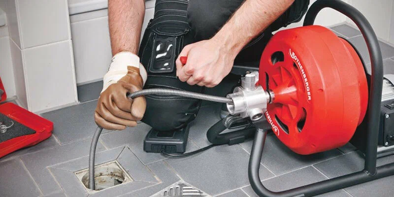 Plumber using a drain-cleaning machine in Warminster