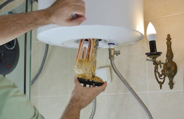 Technician removing mineral buildup from a water heater in Warminster