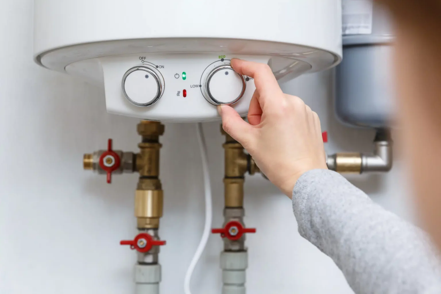 Homeowner adjusting the temperature controls on a water heater in Warminster